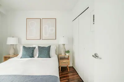 a white bedroom with a bed with blue pillows at 809-5A Gorgeous New 1BR Heart of Midtown in New York