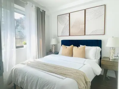 a bedroom with a large bed with a blue headboard at 809-6A NEW 2BR Private Roof & City View in New York