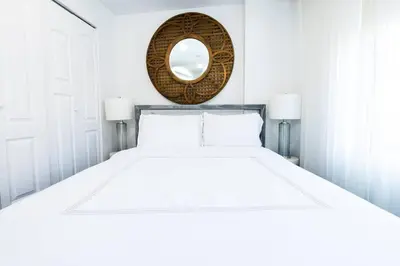 a white bedroom with a large bed and a mirror at 809-6B 2BR Duplex Breathtaking Views Beauty in New York