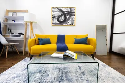 a yellow couch in a living room with a glass table at 69-2D Stylish Lower East Side 1BR Apt BRAND NEW in New York