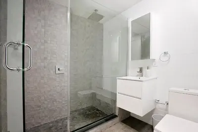 a white bathroom with a shower and a sink at 24-6 Gramercy area Newly reno Studio W D in unit in New York