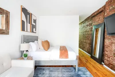 a bedroom with a white bed and a brick wall at 26-3A STUDIO Gramercy W D Outdoor Courtyard in New York
