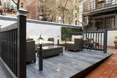 a wooden deck with wicker furniture and a fence at 26-3A STUDIO Gramercy W D Outdoor Courtyard in New York