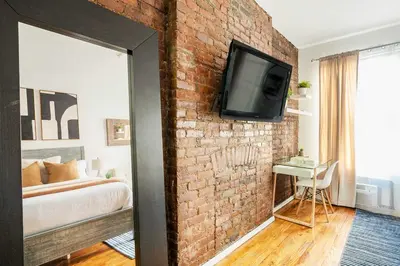 a brick wall in a bedroom with a television on a wall at 26-3A STUDIO Gramercy W D Outdoor Courtyard in New York