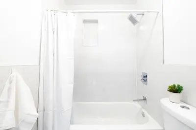 a white bathroom with a white shower curtain and a tub at 26-4A New Studio prime 20's W D Shared Courtyard in New York