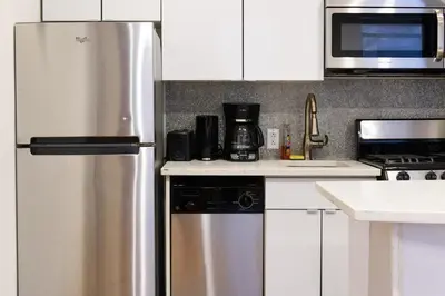 a kitchen with white cabinets and a stainless steel refrigerator at 26-4B Newly Furnished 1BR W D Courtyard in New York