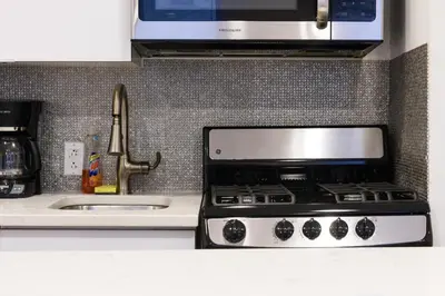 a kitchen counter with a stove and a microwave at 26-4B Newly Furnished 1BR W D Courtyard in New York