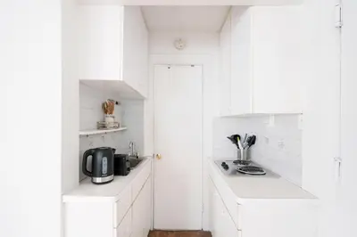 a white kitchen with white cabinets and a sink at 11-4F Prime west village designer 1BR in New York