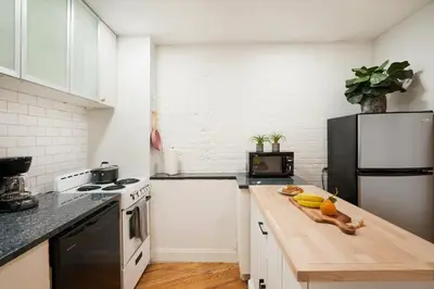 a kitchen with a wooden counter top and a black refrigerator at 139-2W Prime west village Furnished 2BR Best value in New York