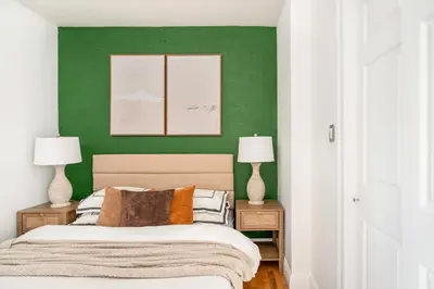 a bedroom with a green wall and a bed with two lamps at 139-3E west village 1BR best value in New York