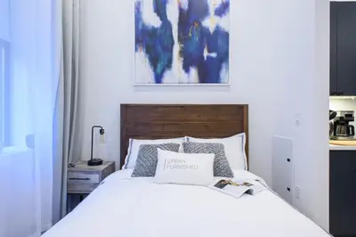 a bedroom with a white bed with a wooden headboard at 3-2 NEW Prime E Village Private outdoor! in New York
