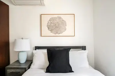a bedroom with a bed with a black pillow and a lamp at 39-3 Newly renovated 3 BR Prime midtown sleeps 6 in New York