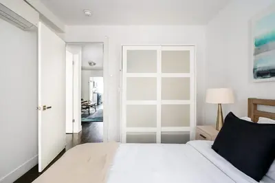 a white bedroom with a bed and a door at 39-3 Newly renovated 3 BR Prime midtown sleeps 6 in New York