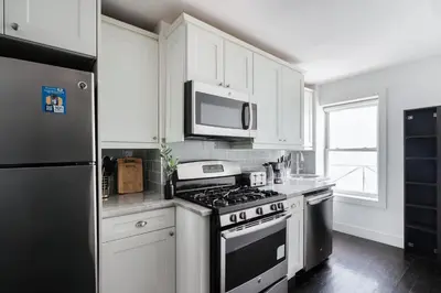 a kitchen with white cabinets and a stove and a microwave at 39-3 Newly renovated 3 BR Prime midtown sleeps 6 in New York