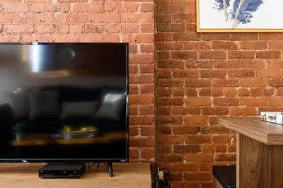 a flat screen tv sitting next to a brick wall at 428-4R prime midtown large 2 BR Newly Furnished in New York