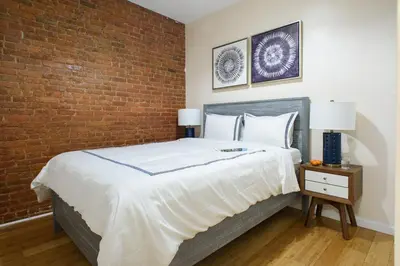 a bedroom with a large bed with a brick wall at 428-4R prime midtown large 2 BR Newly Furnished in New York