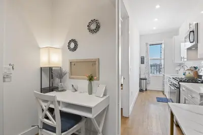 a white kitchen with a white table and a white counter at Chic Penthouse with bus stop at doorstep - 15 Minutes to NYC in Hoboken