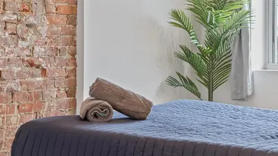 a bed with a pillow and a plant in a room at Chic Penthouse with bus stop at doorstep - 15 Minutes to NYC in Hoboken