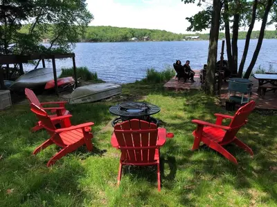 a group of red chairs and a table next to a lake at Lakefront Cabin Pvt Beach and Dock - Sunset Marina in Arrowhead Lake