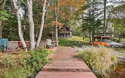 a wooden path with benches and a house in the background at Lakefront Cabin Pvt Beach and Dock - Sunset Marina in Arrowhead Lake