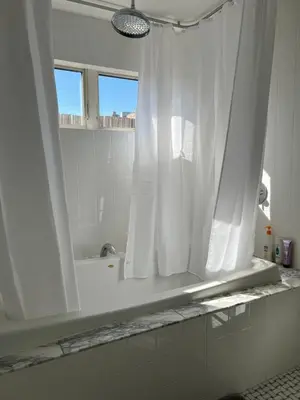 a bathroom with a white shower curtain and a tub at Modern loft style 2bed 2bath minutes to Times Square in West New York