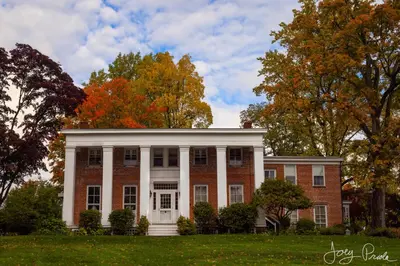 a large red brick house with trees in the background at Cromwell Manor Inn in Cornwall-on-Hudson