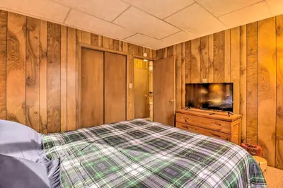 a bedroom with wooden walls and a bed and a tv at Lake Harmony Access Home with Game Room and Fire Pit! in Lake Harmony