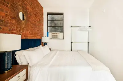 a bedroom with a white bed and a brick wall at 454-4R New 2BR prime midtown Best value Sleeps 5 in New York