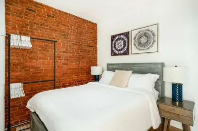 a bedroom with a white bed and a brick wall at 454-4R New 2BR prime midtown Best value Sleeps 5 in New York