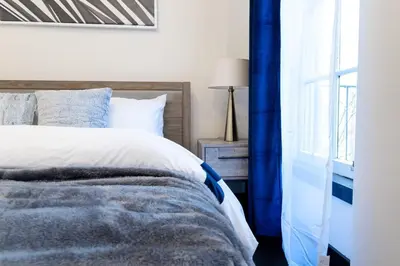 a bedroom with a bed with blue curtains and a window at E10-1 Designer East Village Townhouse 1BR in New York