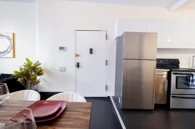 a kitchen with a stainless steel refrigerator and a table at E10-1 Designer East Village Townhouse 1BR in New York