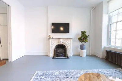 a living room with a fireplace and a tv on the wall at E10-2 Designer East Village Townhouse 1BR W D in New York