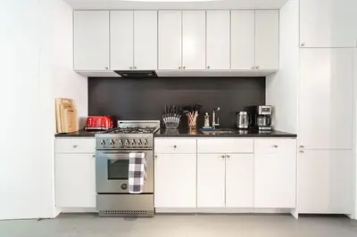 a kitchen with white cabinets and a stove top oven at E10-2 Designer East Village Townhouse 1BR W D in New York