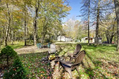 two chairs and a dog sitting in a yard at Pet-Friendly Cabin in Pocono Lake! in Pocono Lake