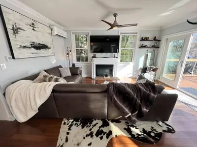 a living room with a brown couch and a fireplace at Cozy Cabin on the Lake w/ HotTub in Hopatcong