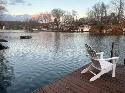 a white chair sitting on a dock next to a lake at Cozy Cabin on the Lake w/ HotTub in Hopatcong