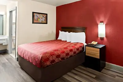 a small room with a bed with a red wall at Bellmawr Economy Inn Bellmawr-Philadelphia Area in Bellmawr