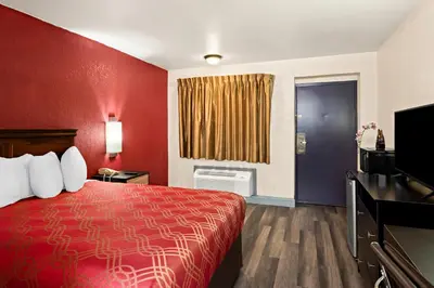 a hotel room with a red bed and a television at Bellmawr Economy Inn Bellmawr-Philadelphia Area in Bellmawr