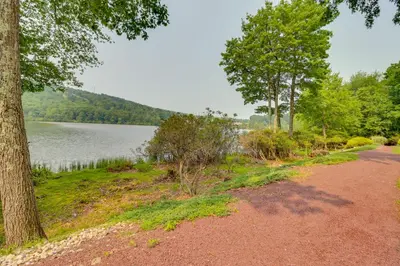 a dirt road next to a lake with trees at Steps to Shore Scenic Big Boulder Lake Condo! in Lake Harmony