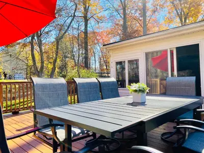 a wooden table on a deck with chairs and an umbrella at Cedar Mill Hideaway in Woodbury