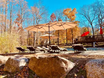 a patio with chairs and an umbrella next to a pool at Cedar Mill Hideaway in Woodbury