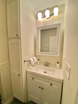 a white bathroom with a sink and a mirror at Cedar Mill Hideaway in Woodbury