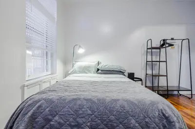 a white bedroom with a bed and a ladder at Park Side Living, Get Cozy! in New York