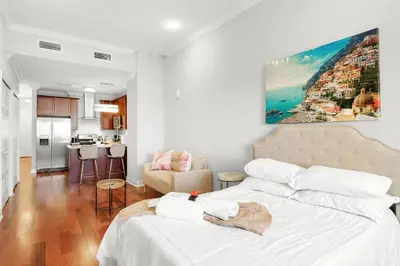 a bedroom with a white bed and a kitchen at XL Studio - Studio with Pool & Scenic Rooftop in Philadelphia