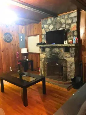 a living room with a stone fireplace with a tv at Rare River Views & Access, Cabin by Eden Islands in Montague
