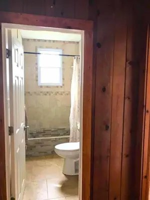a bathroom with a toilet and a window at Rare River Views & Access, Cabin by Eden Islands in Montague