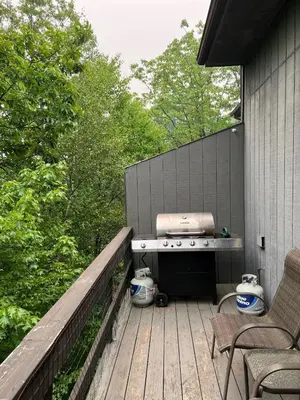 a barbecue on a wooden deck with a fence at Modern 3BR Townhouse Near Kalahari, Aquatopia & Great Wolf in Tannersville