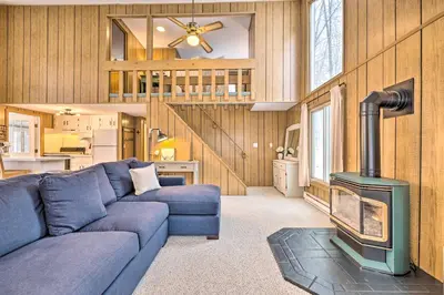a living room with a blue couch and a stove at 1 Block to Lake Poconos Getaway with Fire Pit! in Pocono Lake