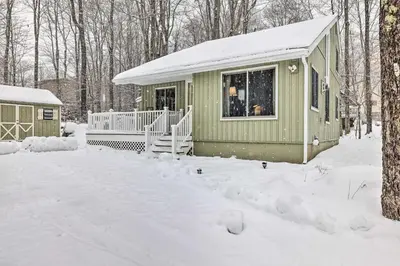 a green cabin in the snow in the woods at 1 Block to Lake Poconos Getaway with Fire Pit! in Pocono Lake