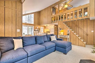 a living room with a blue couch and a staircase at 1 Block to Lake Poconos Getaway with Fire Pit! in Pocono Lake
